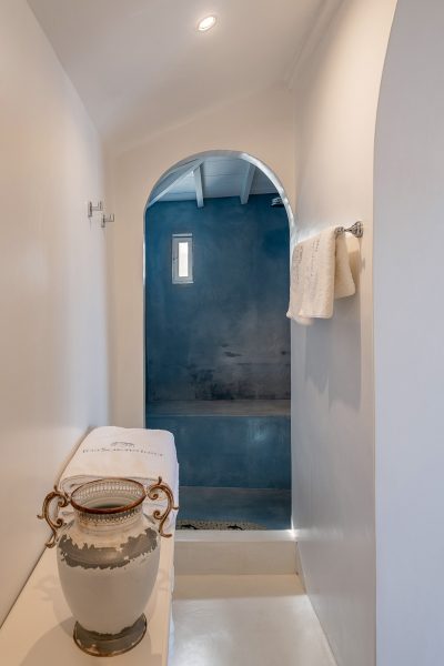 Villa hallway leading to bath, towels and clay pot on table.