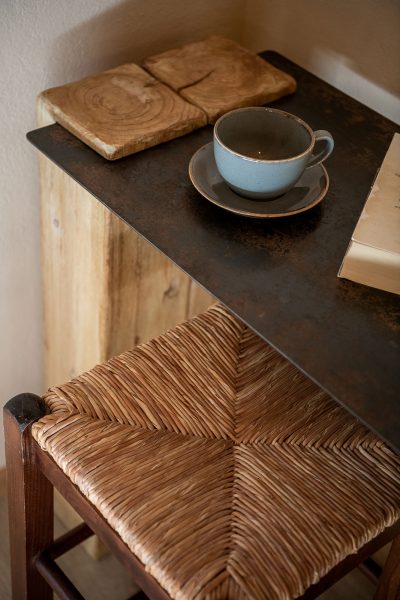 Winter suite, teacup on top of wood and steel table with wooden stools.